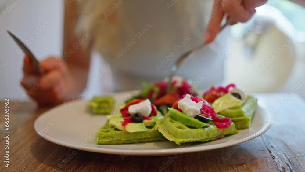 Close-up, woman eats waffles, cuts with a knife and takes with a fork Tasty vegan breakfast. Close up Whole grain tasty waffles with olives and cheese and Salad leaves. Close-up, woman eats waffles, cuts with a knife and takes with a fork Tasty vegan breakfast. Close up Whole grain tasty waffles with olives and cheese and Salad leaves.