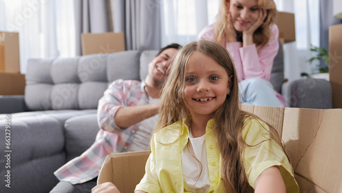 Cute little girl sit inside carton box. Family move into house. Nice kid look at camera. Happy child portrait. Buyer rent home. Tenant buy real estate concept. Fun joy face smile. People bought flat. photo