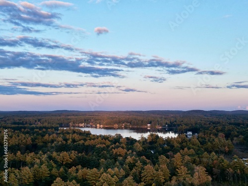 aerial of lake in the distance surrounded by trees during sunset