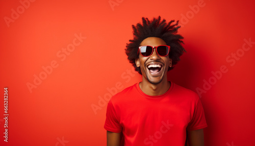 portrait of a happy smiling mixed race young man in sunglasses and red t-shirt on red solid background with copy space