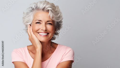 Portrait of a happy smiling beautiful aging mature woman with smooth healthy face skin and gray hair on white background with empty copy space photo