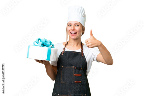 Young pastry blonde woman with a big cake over isolated chroma key background with thumbs up because something good has happened