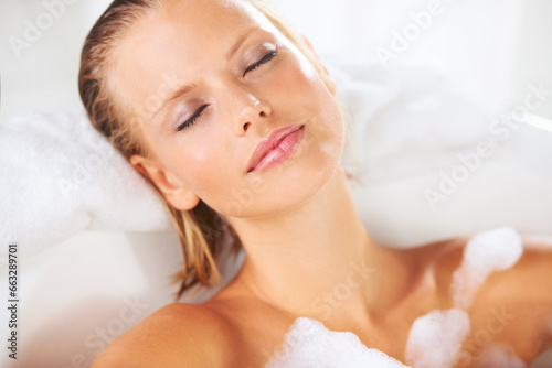 Foam, woman and calm in bubble bath bath with cleaning, skincare and shampoo treatment with rest. Wellness and sleep of a female person with soap in a bathroom for hair wash and relax with nap