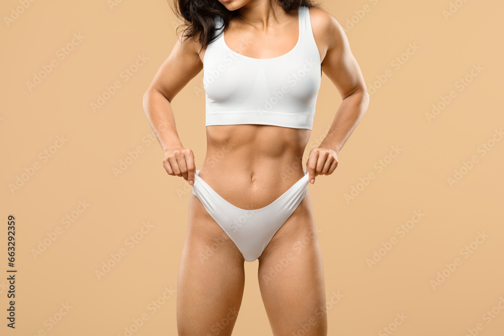 Obraz premium Unrecognizable fit woman with slim body in underwear pulling up white panties
