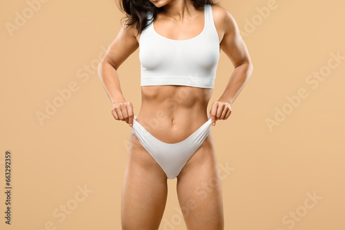 Unrecognizable fit woman with slim body in underwear pulling up white panties