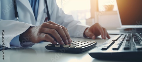 Smart doctor hand using calculator for medical costs in modern hospital photo
