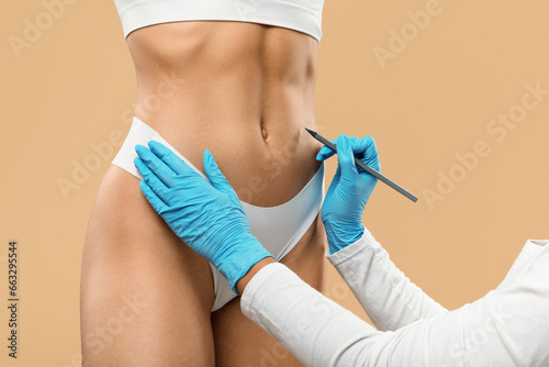 Photos Doctor drawing marks on female stomach, preparing for cosmetic surgery operation