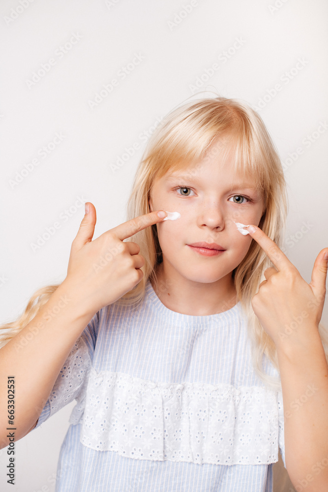 Close-up of a girl gently rubbing moisturizer on her face, promoting natural beauty. Close-up of a girl gently rubbing moisturizer on her face, promoting natural beauty.