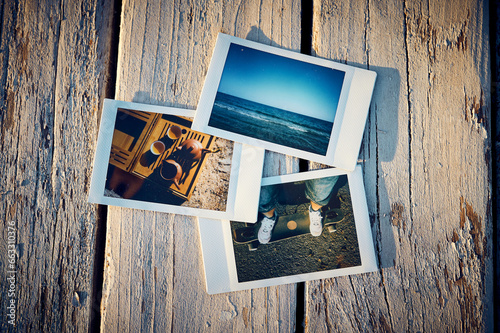 A several instant photographs lie on a wooden table.