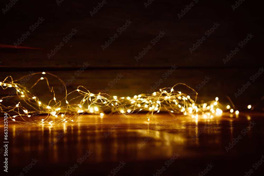 Blurred golden lights on dark wood. Abstract christmas background with empty wooden table. Use for products decorations.