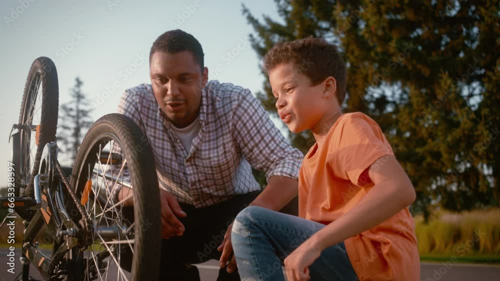 Multiracial father and his son preparing bicycle for ride Multiracial father and his son preparing bicycle for ride