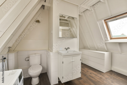 a bathroom in a small room with wood flooring and white walls  there is a mirror on the wall