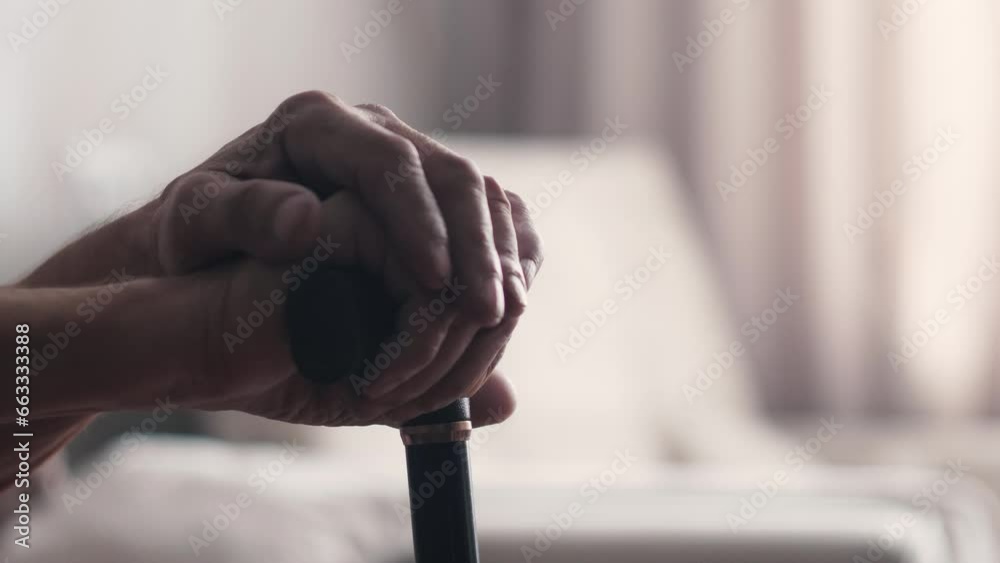 Elderly person's hand holding a walking stick.  Senior man's hand hording an old wood cane to support himself as he walks, great details.