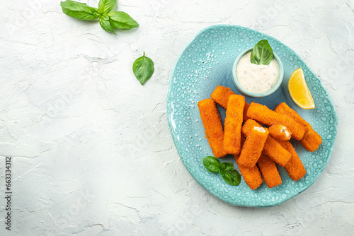 Crumbed fish sticks served with lemon and tartar sauce. Long banner format. top view photo