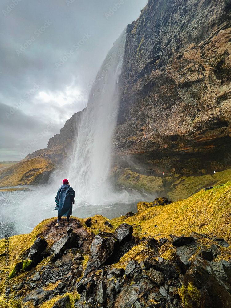 A man standing on a rock near a waterfall.