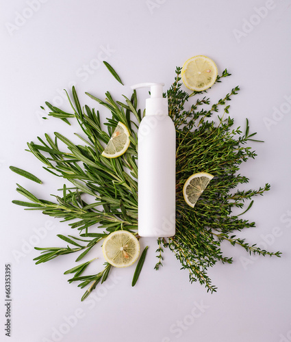 White bottle with cosmetics in thyme and rosemary with lemon natural composition on a white background top view for cosmetics