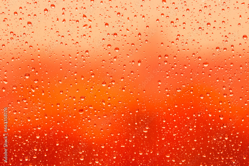Water drops on glass surface over blurry colored background