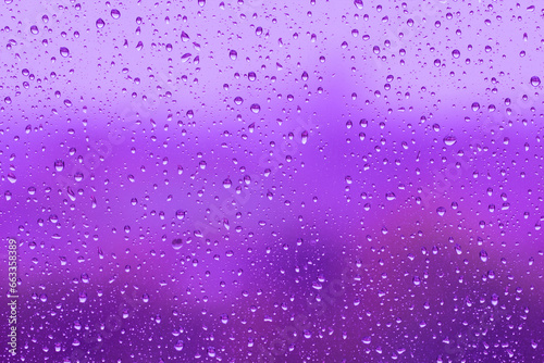 Water drops on glass surface over blurry colored background