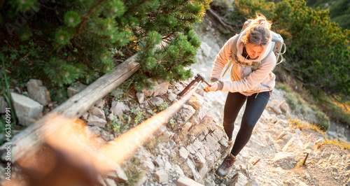 Junge Frau klettert am Klettersteig und sichert sich an einem Stahlseil