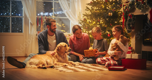 Happy Little Family Exchanging Gifts on Christmas Eve: Brother and Sister Receiving their Gifts. Happy Children Getting New Toys from Mom and Dad, with Family Dog Sharing the Moment