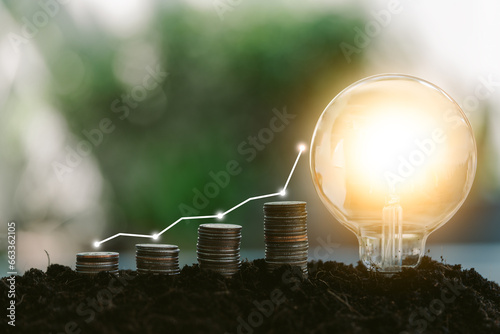 Step stacked coins and light bulbs on the soil with a step up graph, saving finance and energy concept photo