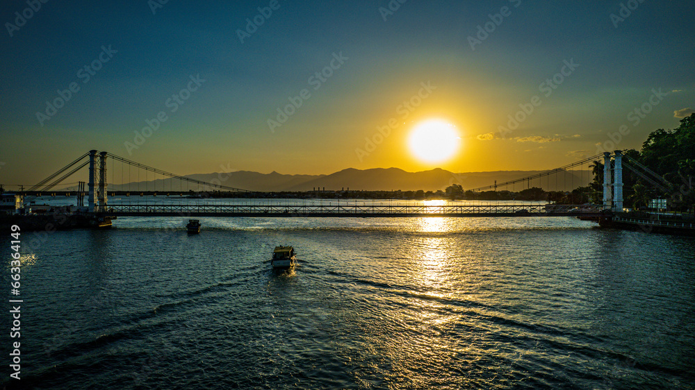sunset over the sea with a Ponte Pensil bridge and boat in São Vicente city