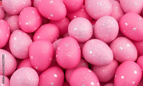 Easter eggs painted pink with glitter, background of holiday symbols