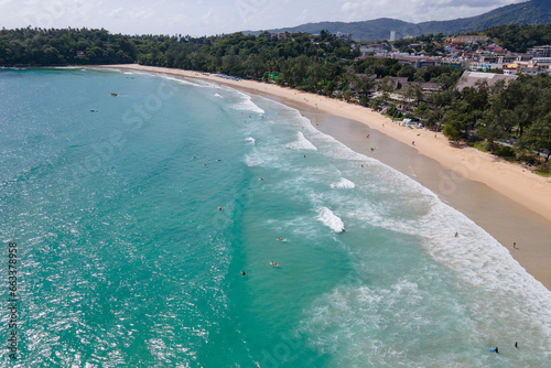 Fotografi Aerial view of Kata Beach with surfers riding waves on surfboards during the low season