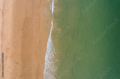 Algarve, Portugal coastline with sandy beach, Atlantic Ocean waves and red cliffs at sunset. Aerial drone view.