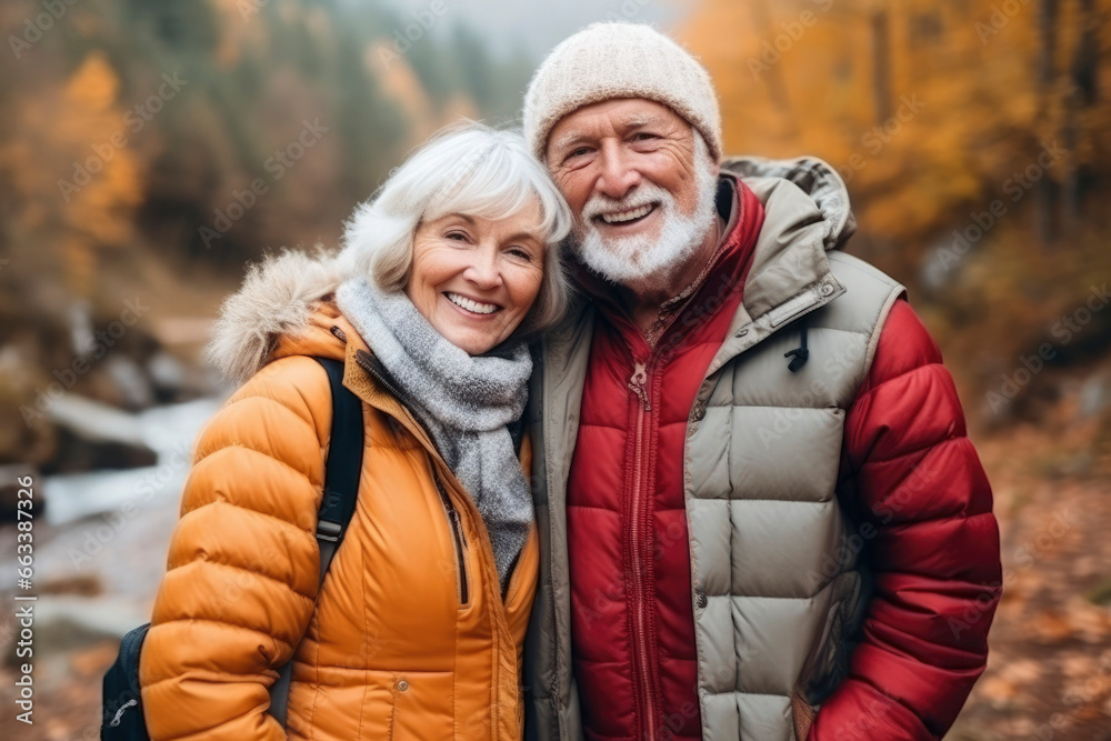 Couple of happy smiling pensioners outdoors in autumn forest, park. Gray-haired man and middle-aged woman are hugging and enjoying life. Concept of active elderly people, traveling