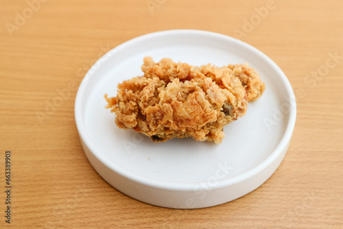 Crispy fried chicken on a white plate on a wooden background