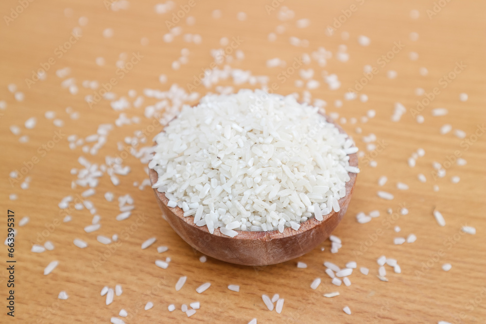 beras or organic rice on a wooden bowl with wooden background. selective focus