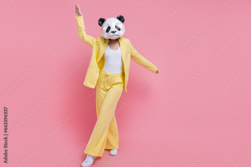 Full length portrait of excited crazy classy person 3d panda mask dancing clubbing empty space ad isolated on pink color background Full length portrait of excited crazy classy person 3d panda mask dancing clubbing empty space ad isolated on pink color background