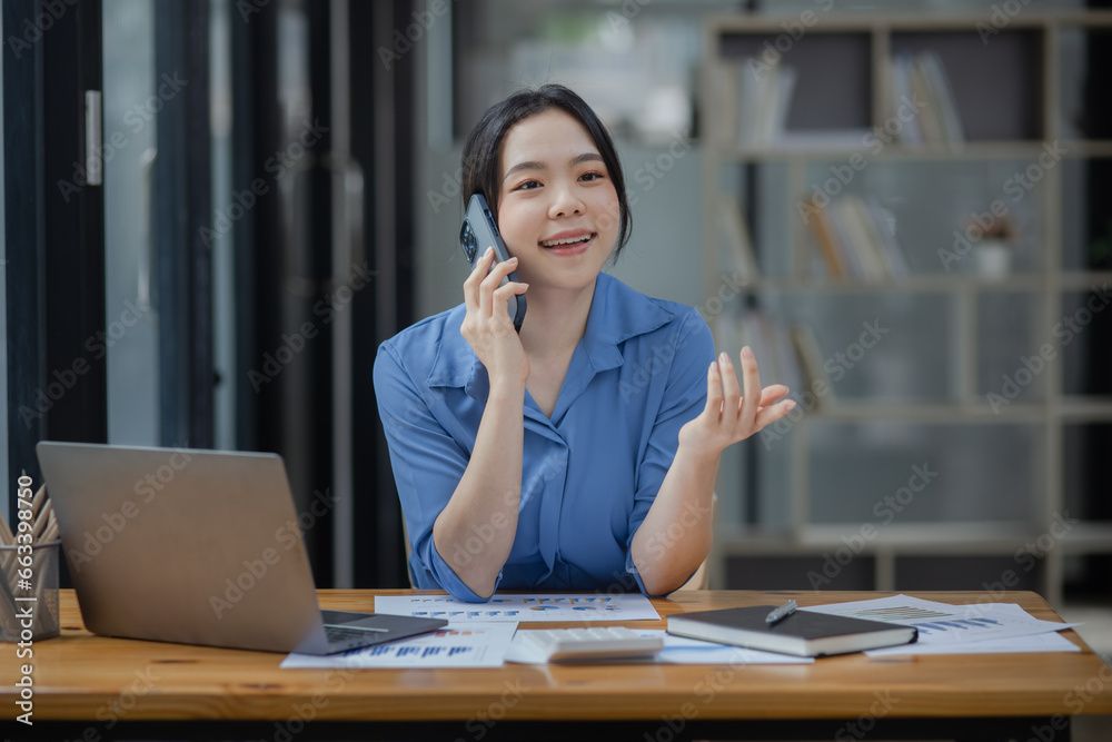 Asian businesswoman using smartphone sitting at desk in office, working online, Asian businesswoman using smartphone sitting at desk in office, working online,