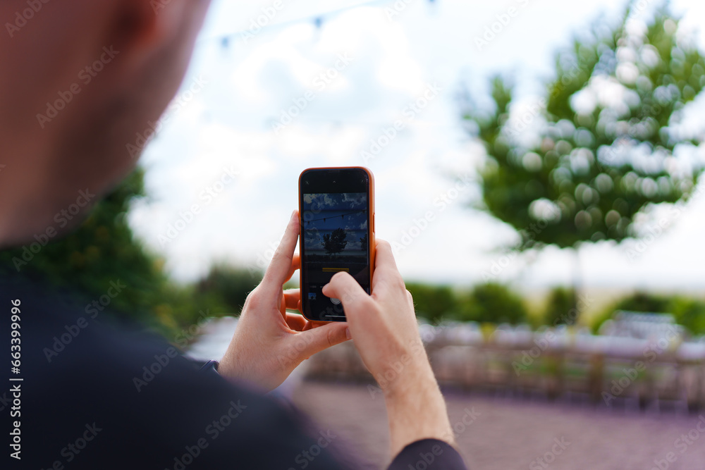 without a face. A man takes a photo of a set table on his smartphone. 