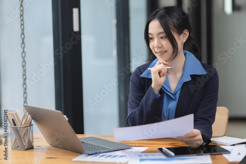 Wallpaper Mural Asian woman working with document papers and laptop sitting at desk workplace office. Torontodigital.ca
