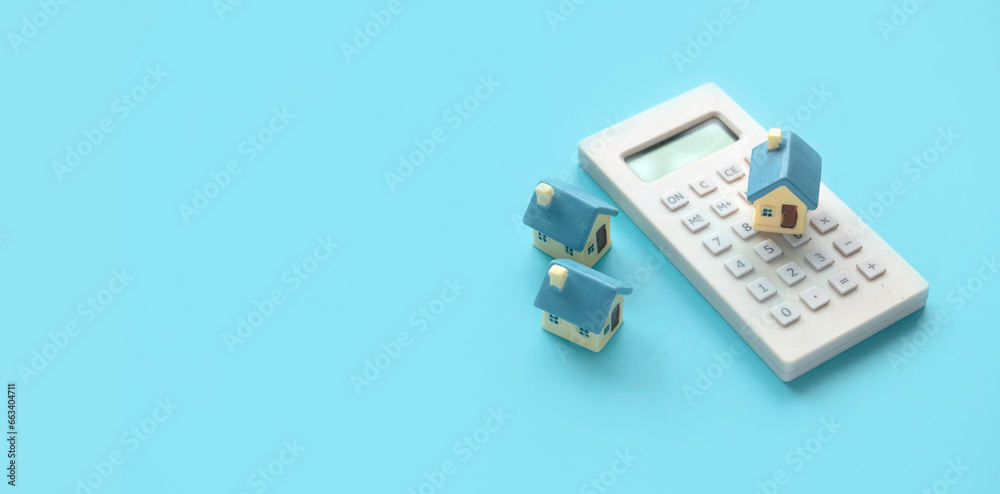 Concept of home loan mortgage, refinance, interest rate. Saving for house.Miniature house with calculator over blue background with copy space. Concept of home loan mortgage, refinance, interest rate. Saving for house.Miniature house with calculator over blue background with copy space.