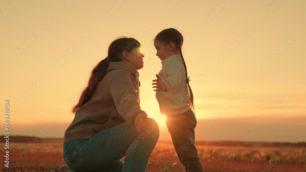 Child playing with mom happy hugs. Family in park in summer. Little child playing with parent. Happy family hugging in front of sun. Carefree childhood, joyful hugs of baby and mother in park, sunset