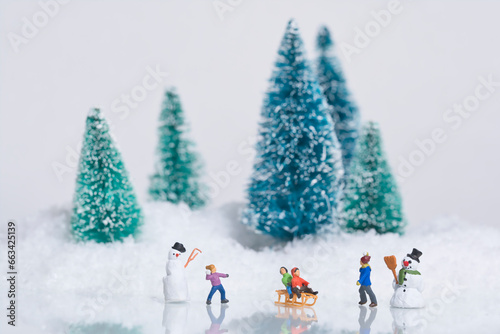 Children play in the snow, with sleighs and snowmen. Miniature figures winter scene