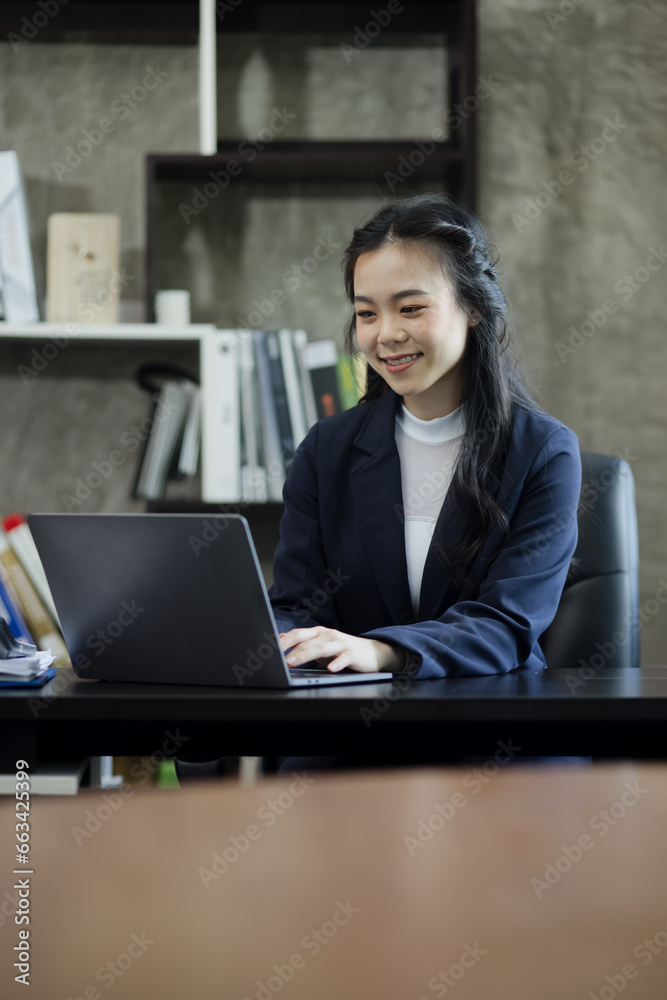 Asian businesswoman using a laptop computer sitting at desk in office. Asian businesswoman using a laptop computer sitting at desk in office.
