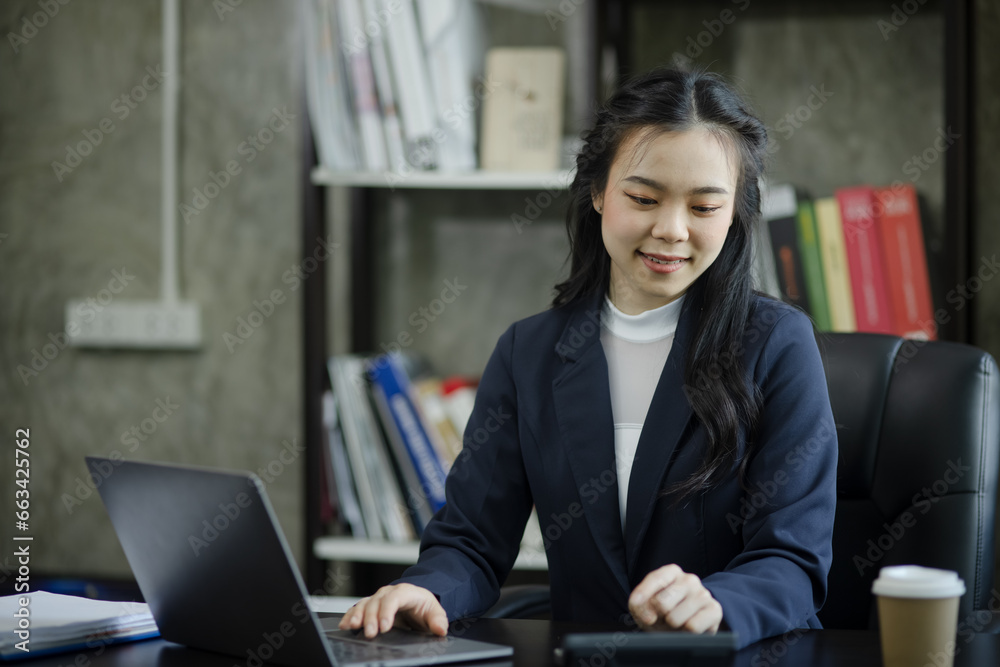 Asian businesswoman using a laptop computer sitting at desk in office. Asian businesswoman using a laptop computer sitting at desk in office.