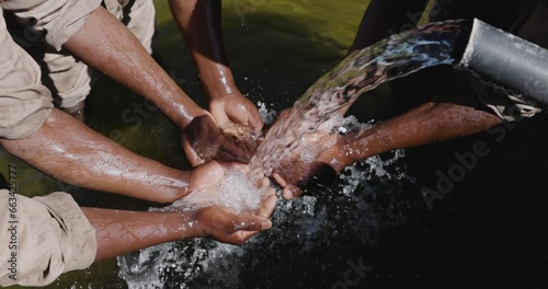 Wallpaper Mural Slow motion. Close-up. Cropped view. Small group of Black peoples hands catching clean running water out a pipe Torontodigital.ca