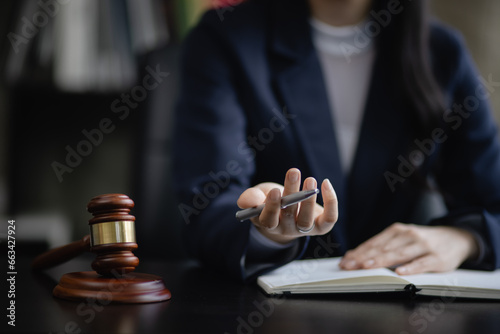 Lawyer woman with a wooden legal gavel on an office desk, justice and law concept.