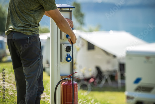 Canvas Print Attaching Camper RV Power Cable to Camping Electric Post During Camping Stay