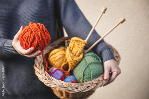 Woman holding ball of wool for knitting or crochet. Colorful yarn in wicker basket photo