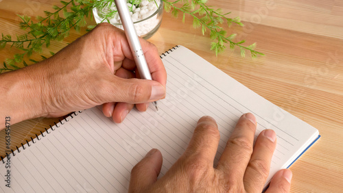 Hands of a left-handed person writing in notebook. Left hand of a person writing in notepad