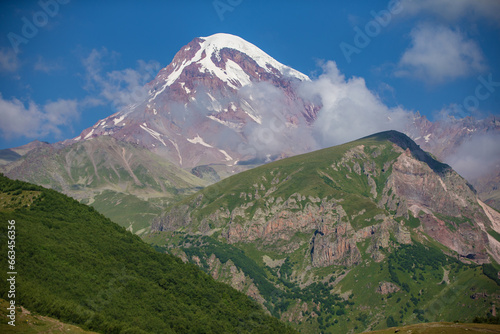 View of Mount Kazbeg in the Caucasus, Georgia. Below the snow-capped peak and the Gergeti glacier, the slopes are deserted and rocky. Calm. Natural remedy. Massive foot of the glacier