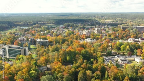 Autumn colours in the city, drone picture of small town covered in multi coloured leafs and river flowing beside