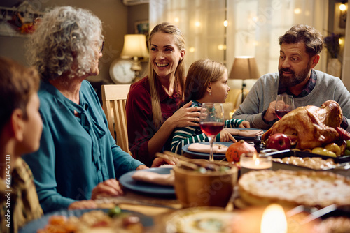 Happy extended family talking while having dinner at dining table on Thanksgiving.