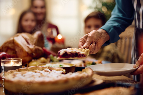 Close up of senior woman serving Thanksgiving pie to her family at dining table. photo